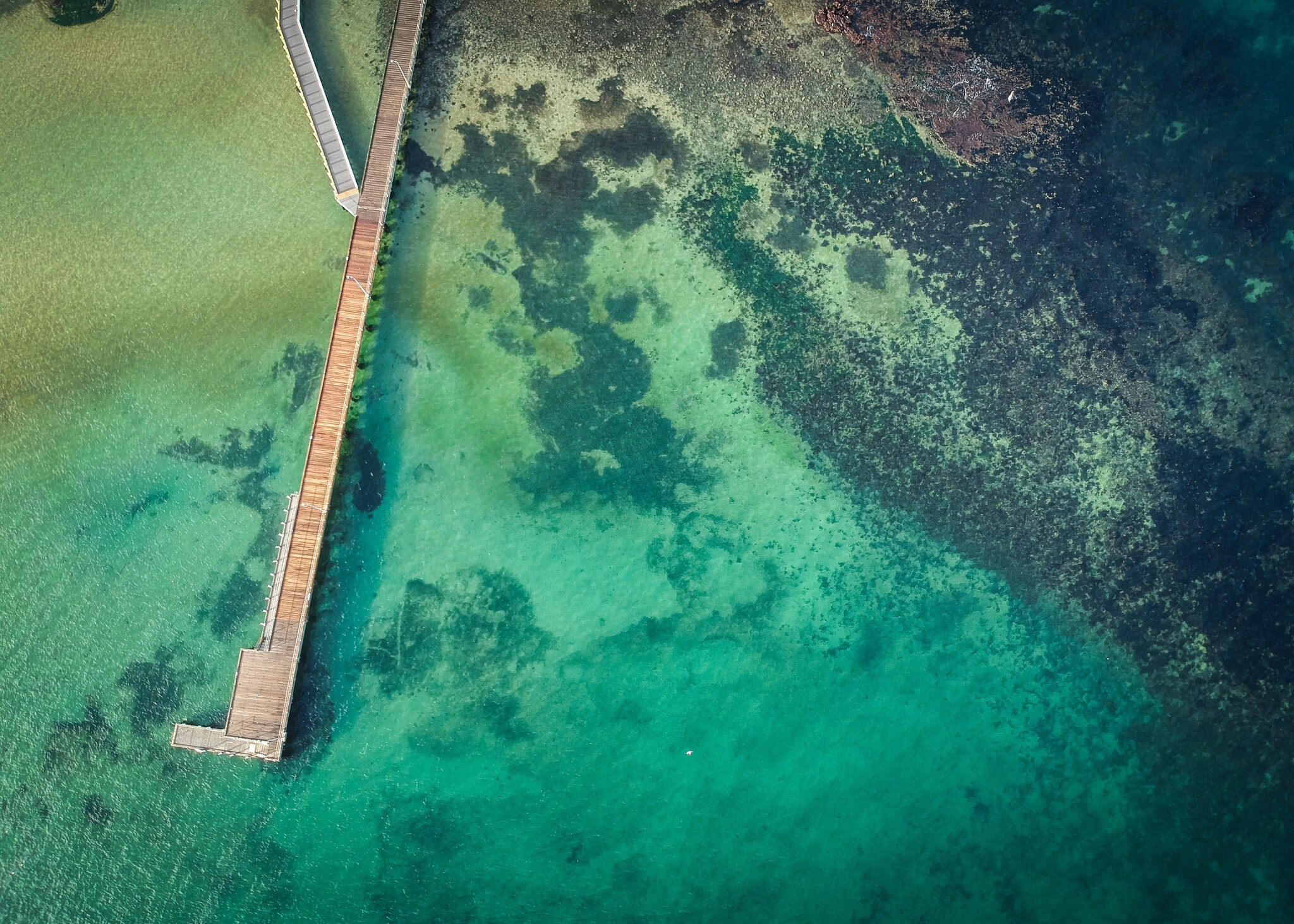 Aerial view of a wooden pier extending into turquoise waters